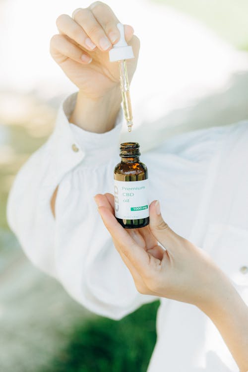 Free A Person Holding Cbd Oil in a Glass Bottle Stock Photo