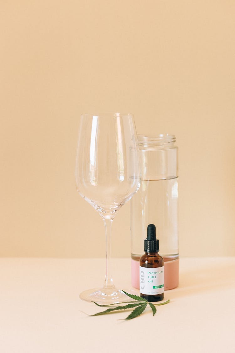 Clear Wine Glass Beside Bottles And Hemp Leaf