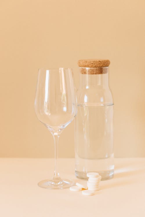 A Glass Near Tablets and a Glass Jar