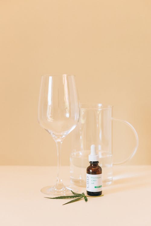Glasses Beside a Small Bottle of Cannabis Oil