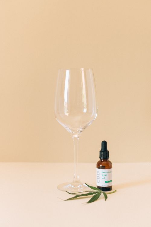 Free A close up of a CBD oil bottle and wine glass with a cannabis leaf against a clean, minimalist background. Stock Photo