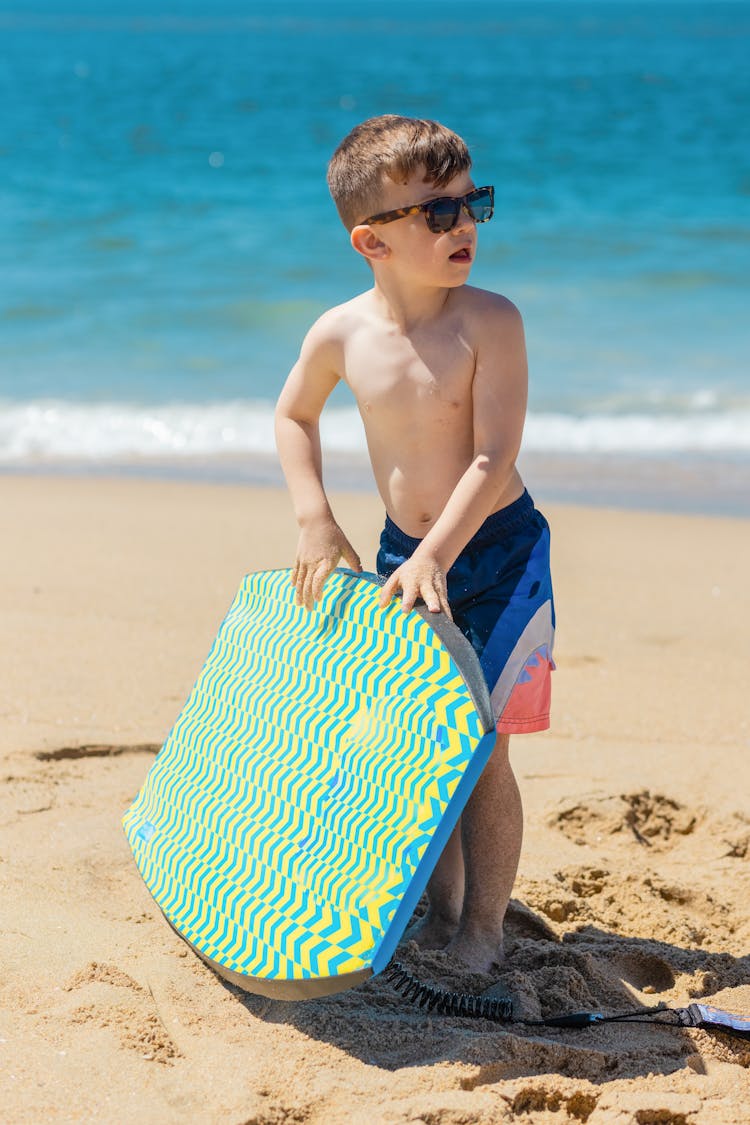 A Boy In Beachwear Holding A Surfboard At The Beach