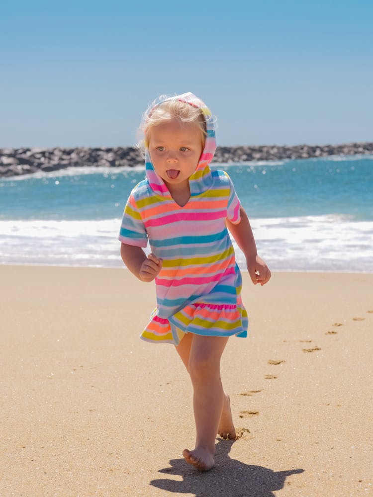 A Kid With Blond Hair Running On The Sand