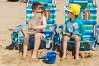Boy in Blue Tank Top Sitting on Blue and Yellow Folding Chair