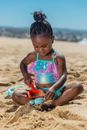 A Young Girl Sitting on the Sand while Playing Toys