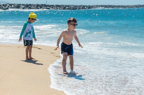 Free Two Boys Standing on the Beach while Having Fun Stock Photo