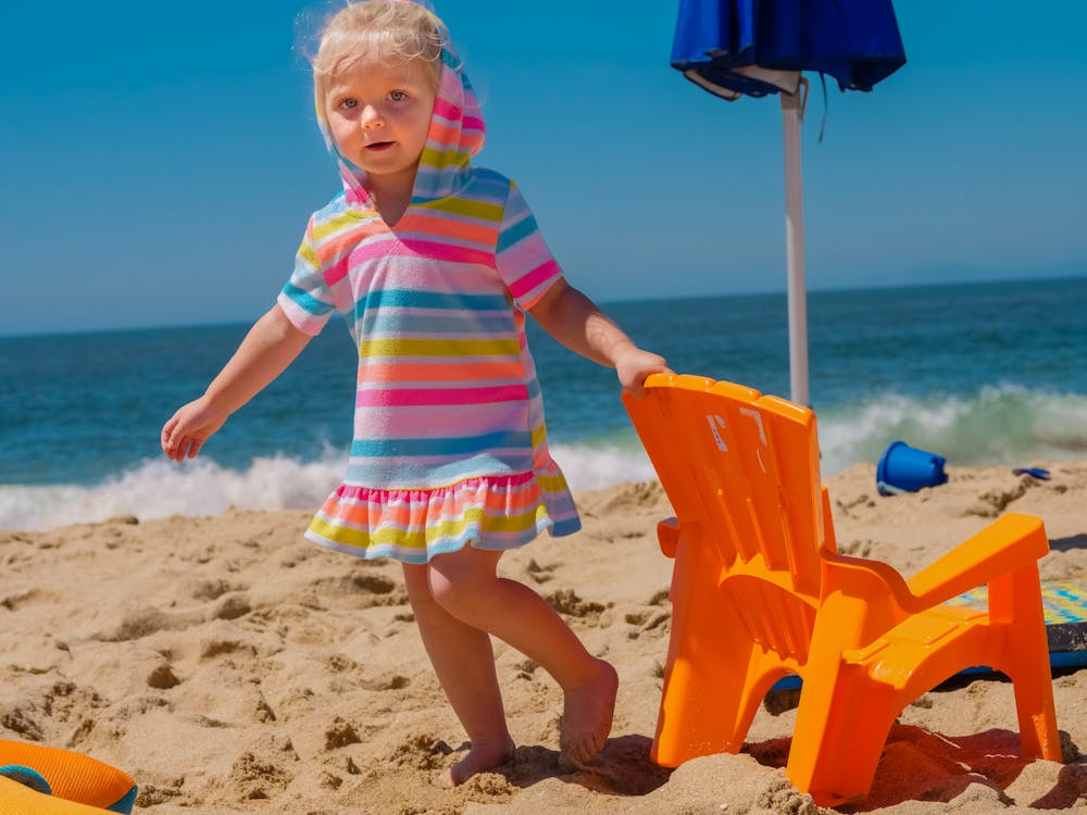 A Girl holding Orange Chair on the Beach