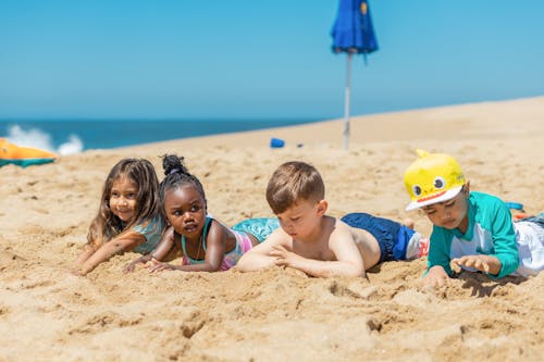 Free Children Lying on Brown Beach Sand Stock Photo