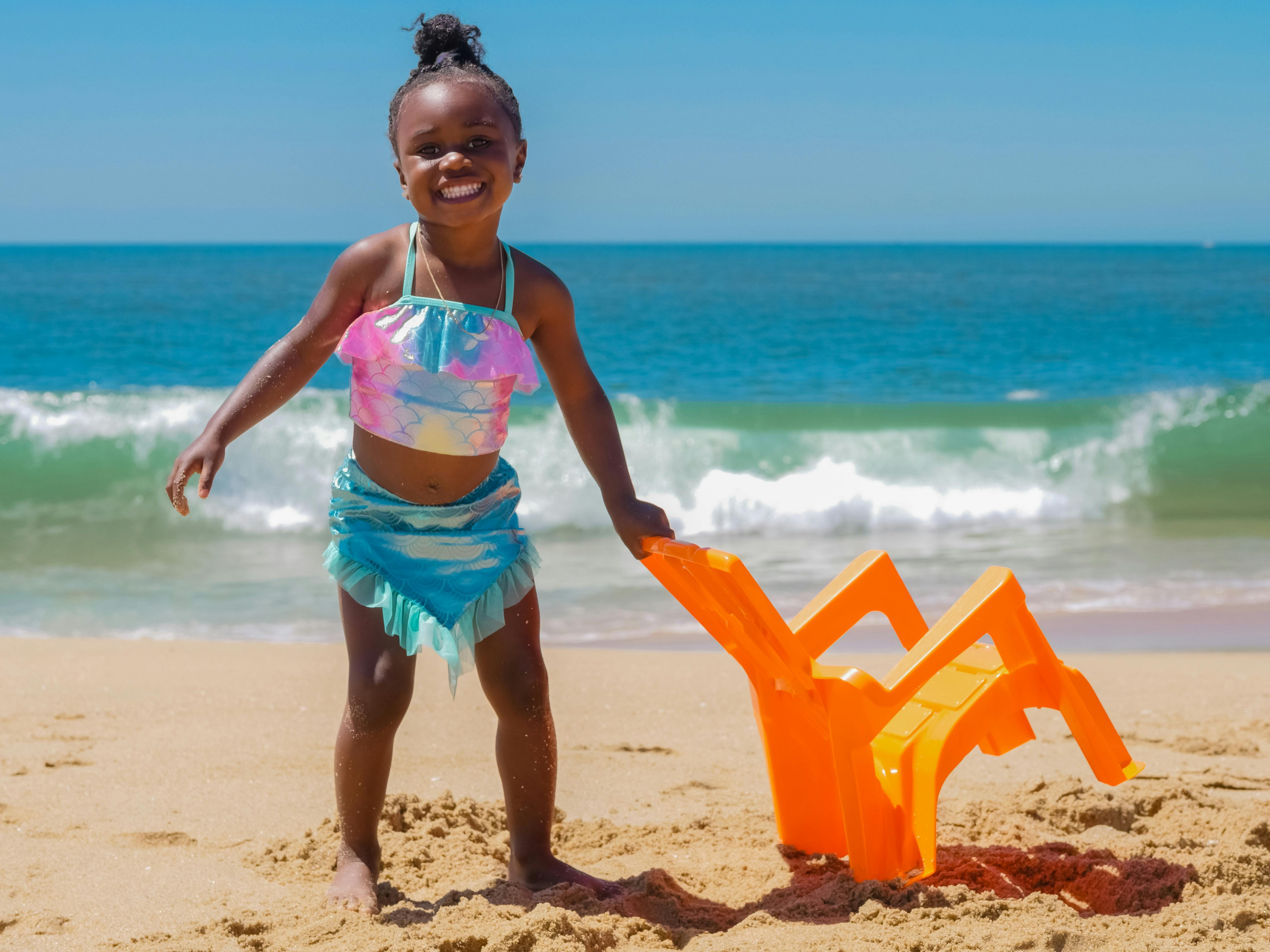 穿着泳装的快乐孩子在海滩上享受阳光明媚的一天，背景是海浪