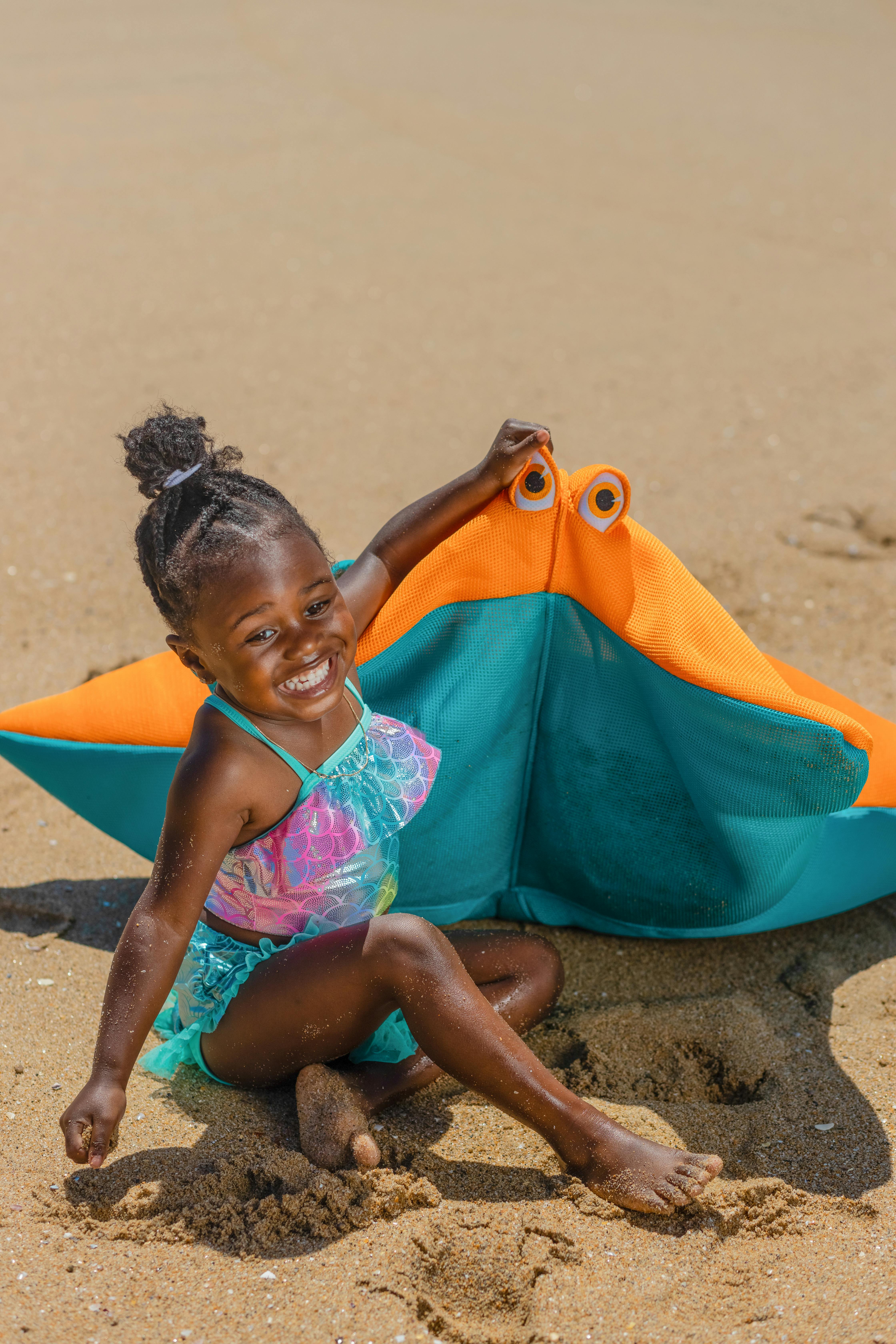 a young girl sitting on the beach sand