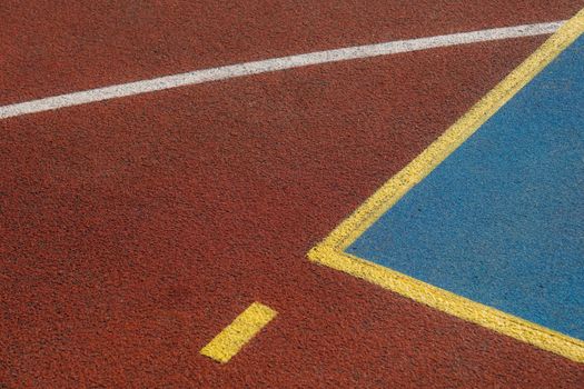 Detailed view of a basketball court's colorful lines and textured asphalt surface for sports backgrounds.