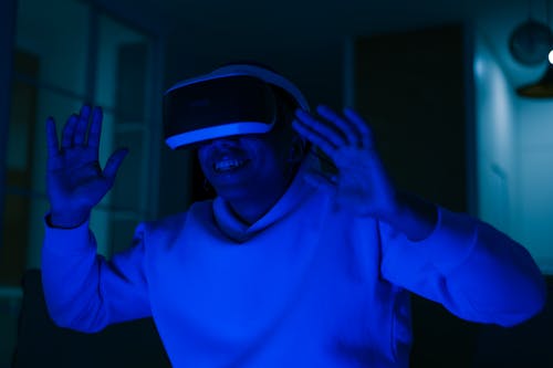 A Man in Hoodie Smiling while Playing Virtual Reality