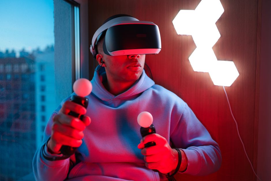 Person using virtual reality headset and controllers indoors. Futuristic gaming technology.