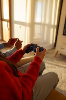 Two people enjoying a gaming session with wireless controllers in a sunlit living room.