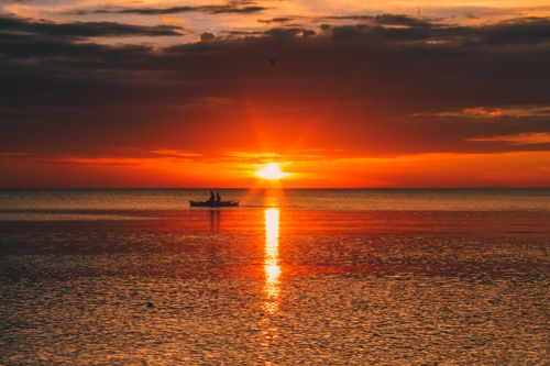 Free A serene sunset over the sea in Northern Mindanao, Philippines, capturing a boat silhouette on calm waters. Stock Photo