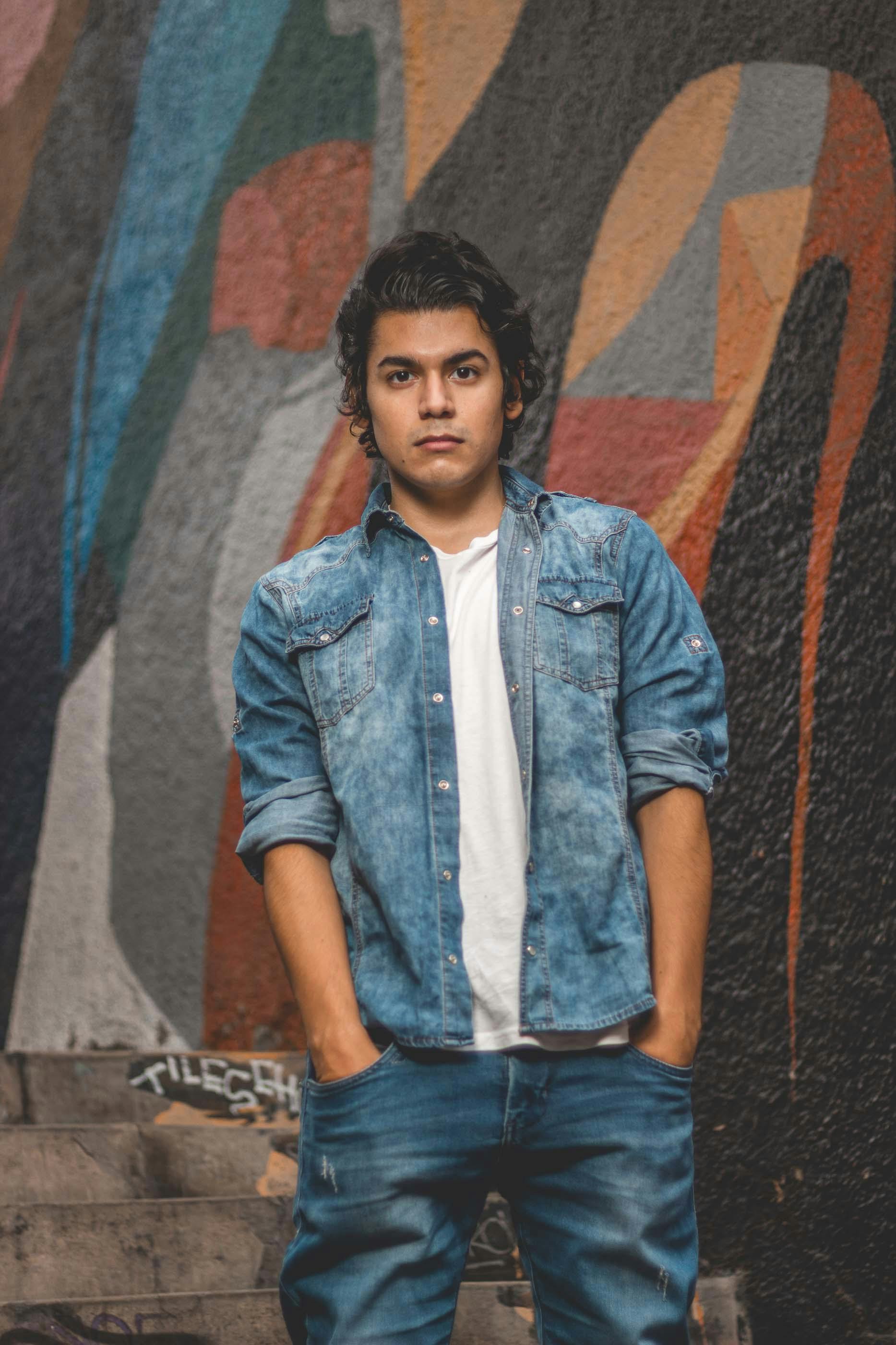 Man in denim posing against colorful graffiti in Barranco, Peru.