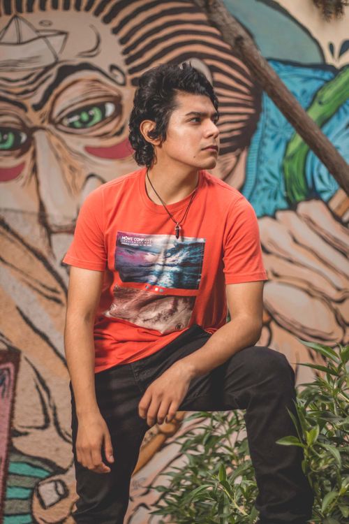 Free A young man poses confidently against a colorful mural in Barranco, Lima, showcasing street art fashion. Stock Photo