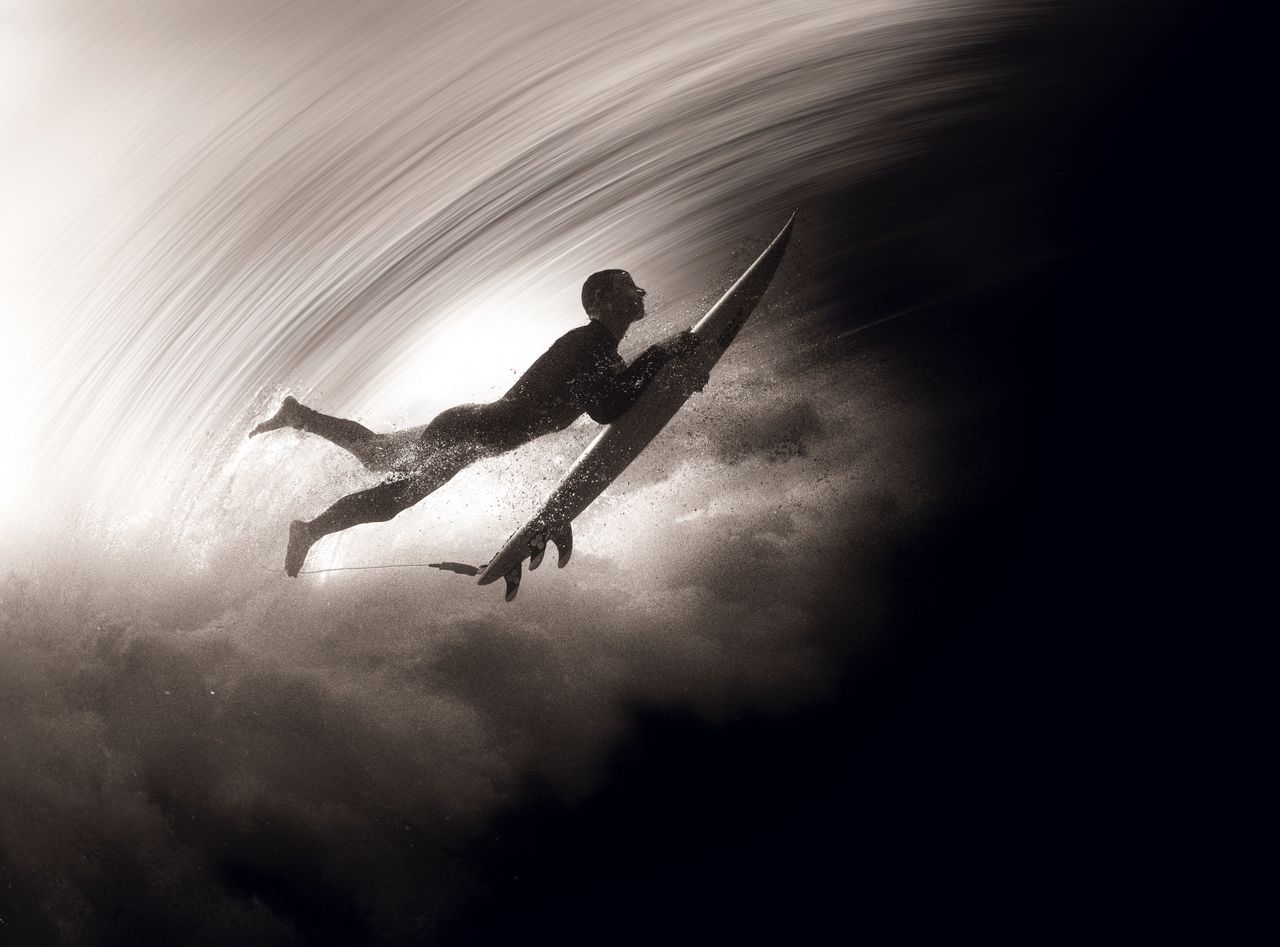 a dynamic underwater view of a surfer duck diving under a wave capture