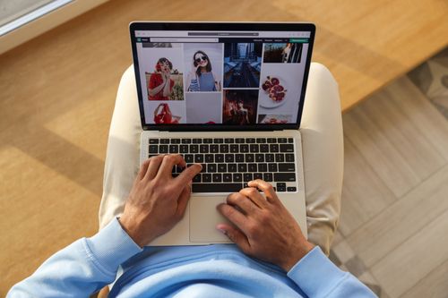 Free A man casually browsing an online store on a laptop, showing a variety of images. Stock Photo