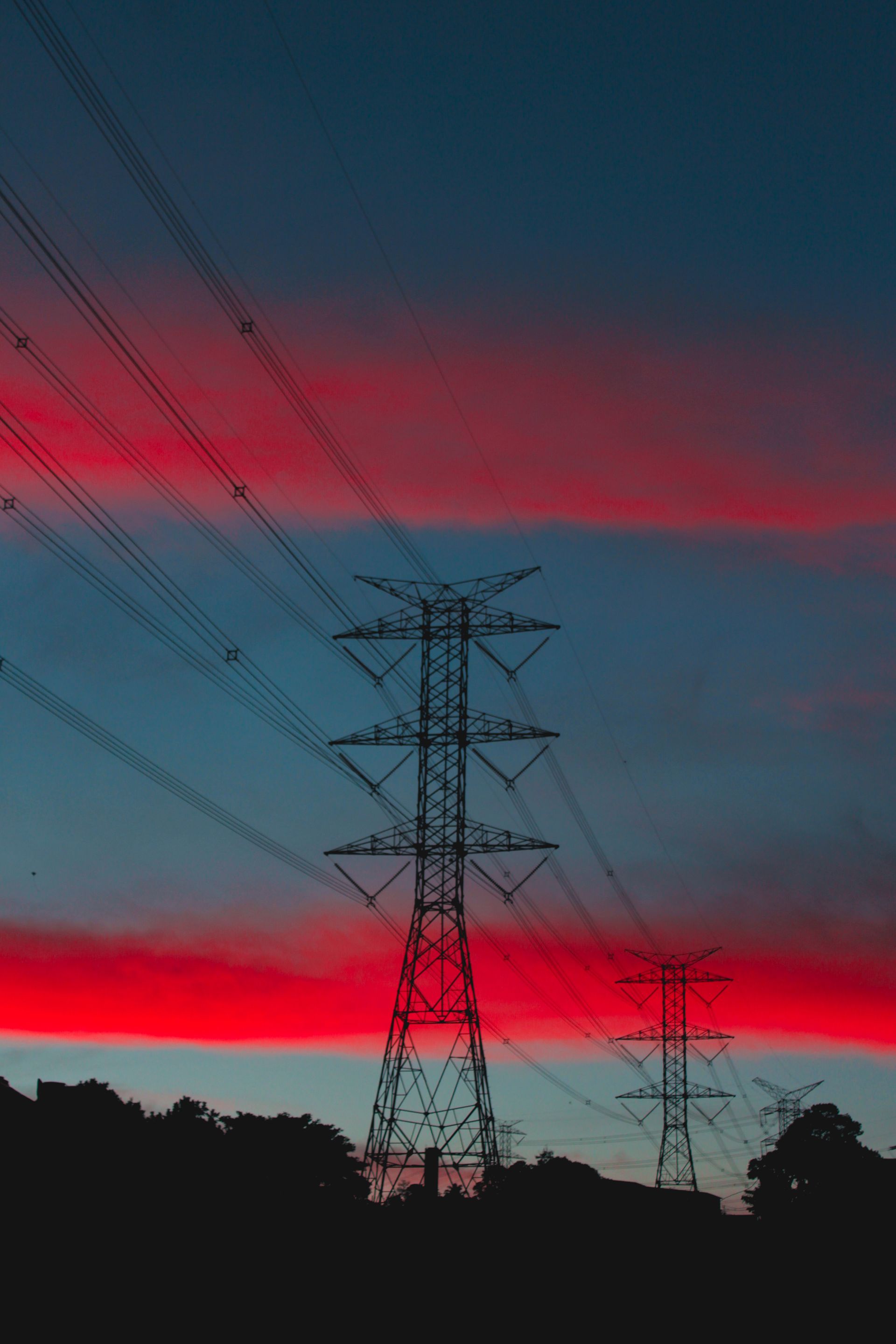 Dramatic transmission tower silhouette against red and teal sky