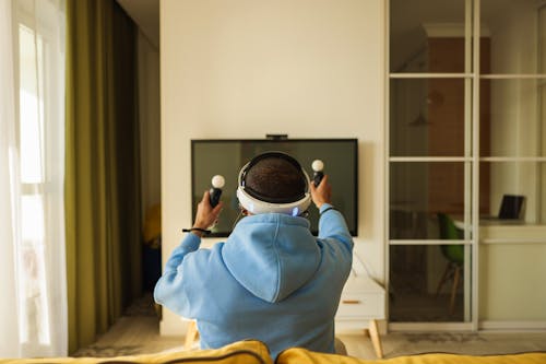 Man in Blue Hoodie Sitting on Couch Playing Virtual Reality 