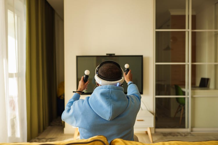 Man In Blue Hoodie Sitting On Couch Playing Virtual Reality 