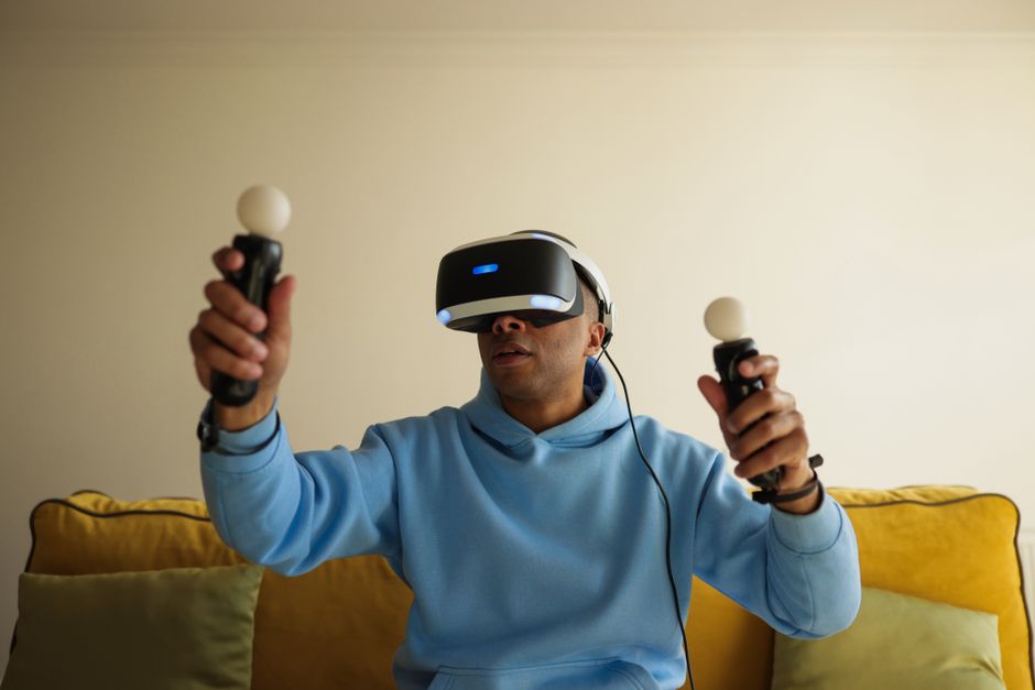男性が室内でヘッドセットとコントローラーを使ってバーチャルリアリティゲームを楽しんでいます。