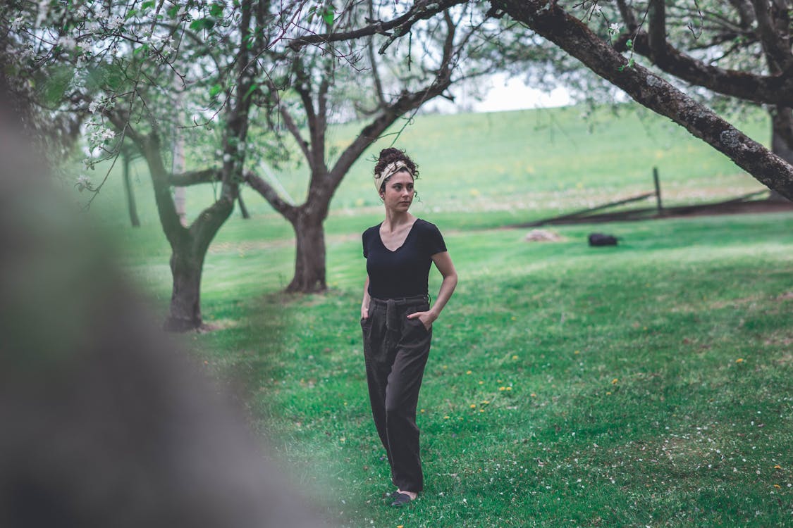 Woman Wearing a Black Top and Brown Pants on Green Grass