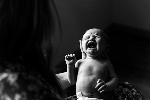 Free Grayscale Photo of Person Holding a New Born Baby Stock Photo