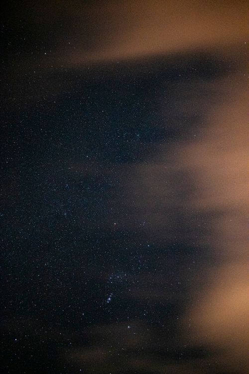 Free A serene starry night sky with scattered clouds, captured in the desert landscape of Algeria. Stock Photo