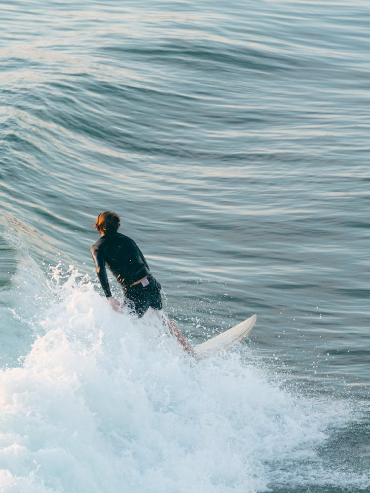 Man In Black Wetsuit Surfing On Sea