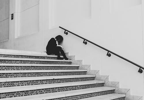 Free Grayscale Photo of a Person Sitting on the Stairs Stock Photo