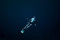 一名自由潜水员探索深海的蓝色水域，展示水下自由