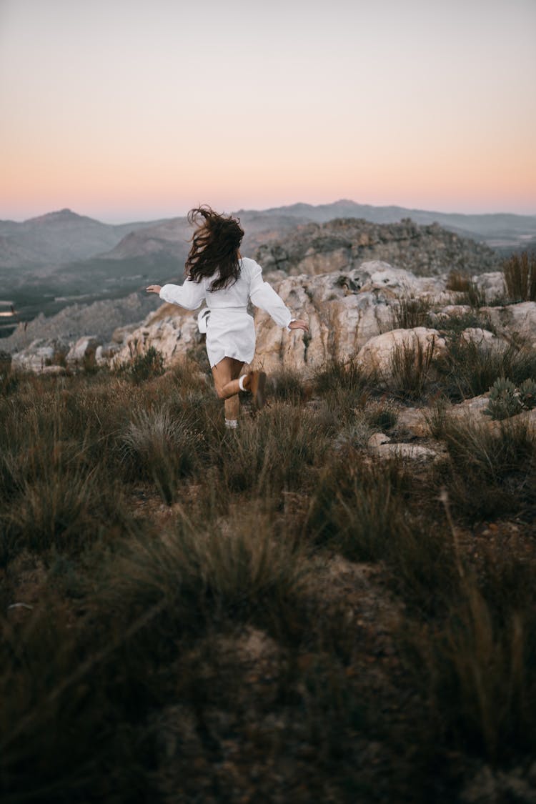 Back View Of A Woman Running On Green Grass