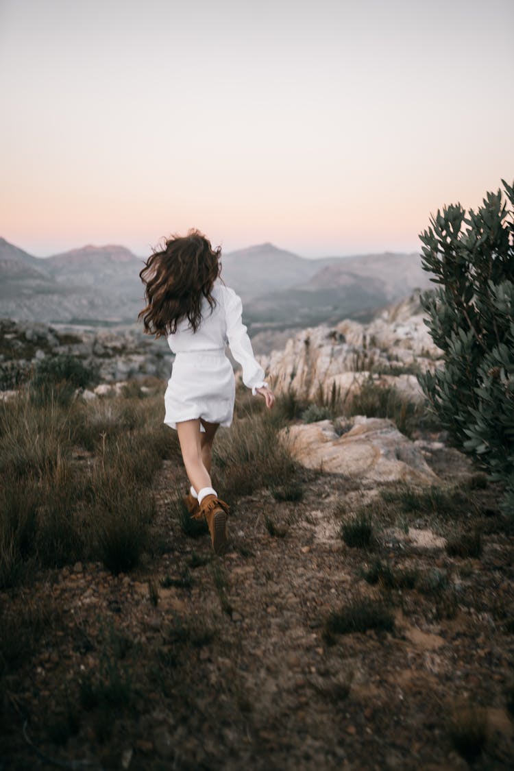 Back View Of A Woman In A White Dress Running