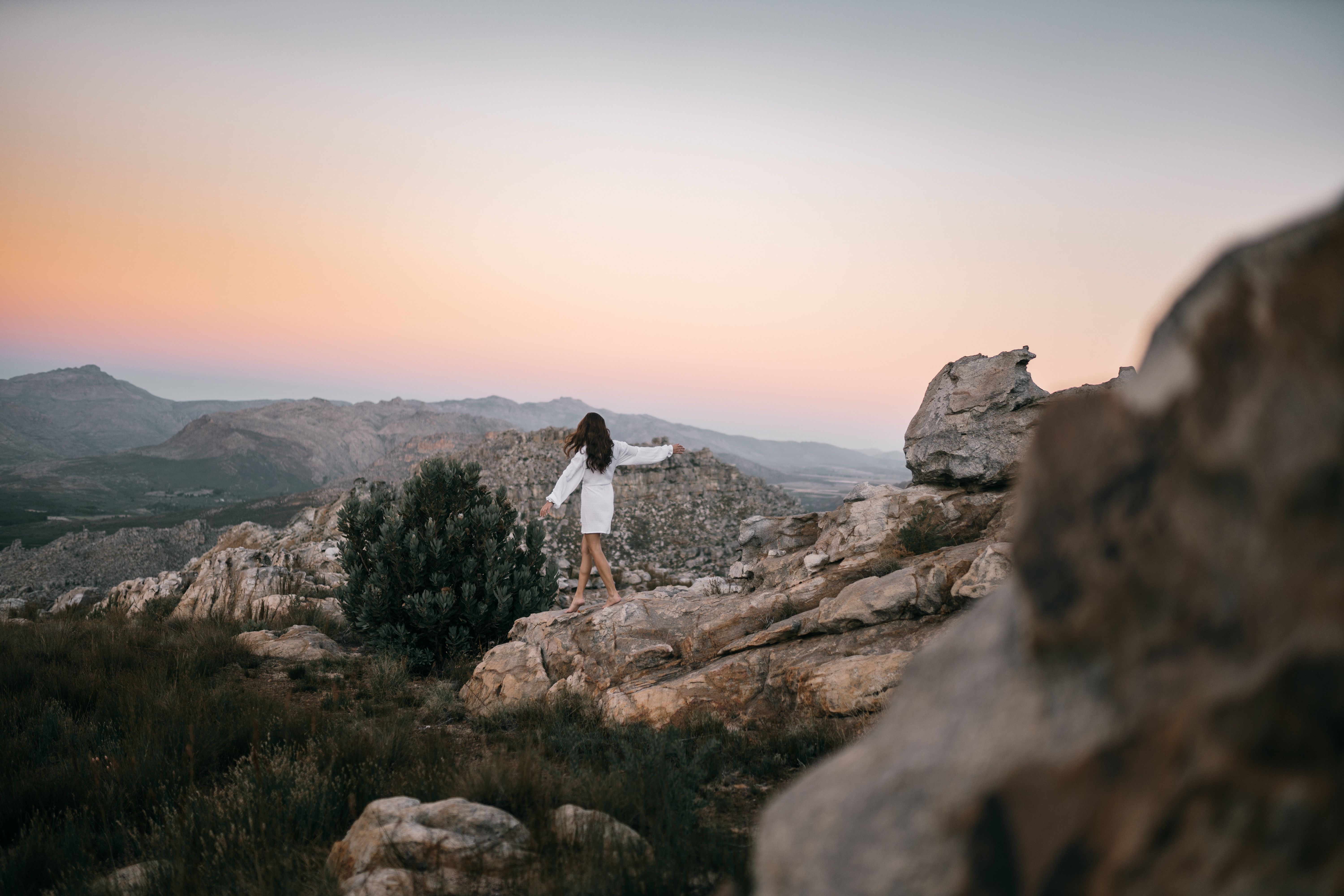 Woman in White Dress Standing on Rocky Mountain Cliff · Free Stock Photo