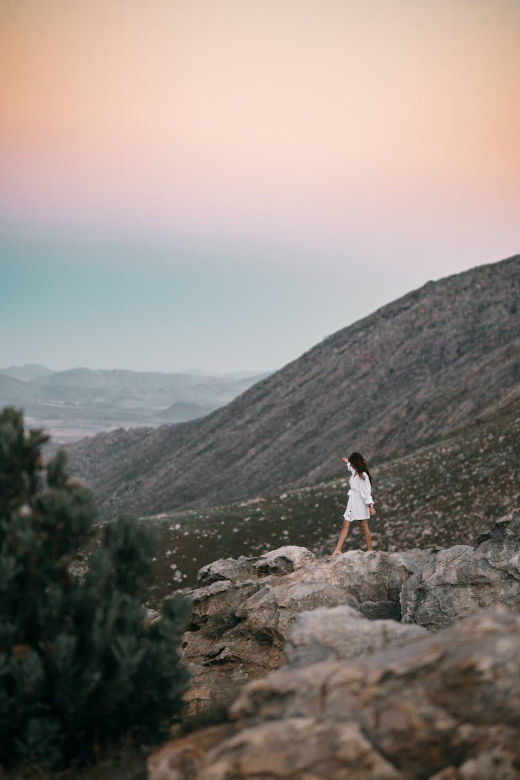 A Woman Balancing While Walking On Rocks