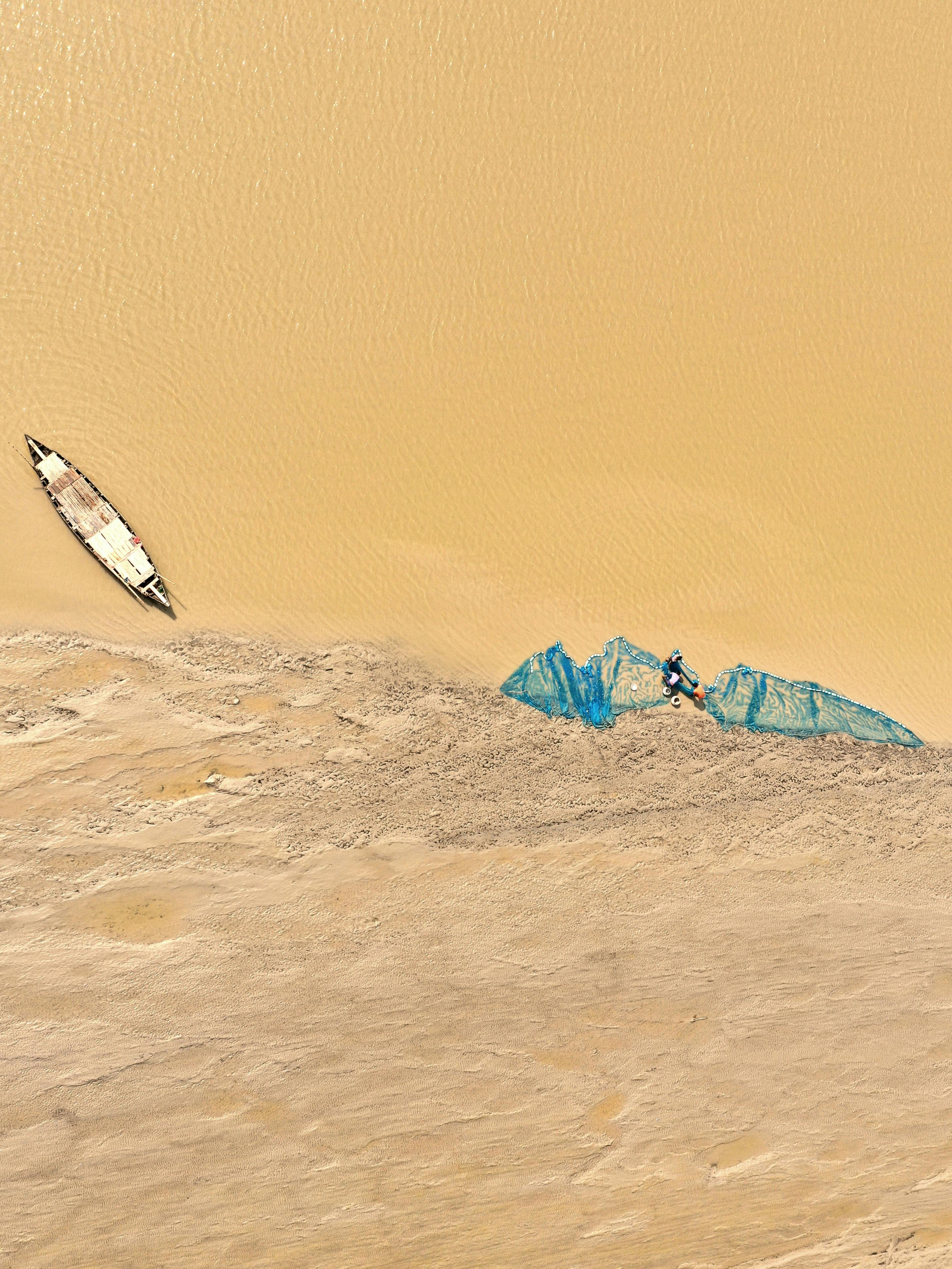 aerial view of a beige flood water and sand with a canoe and blue net