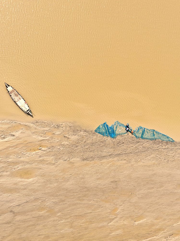 Aerial View Of A Beige Flood Water And Sand With A Canoe And Blue Net