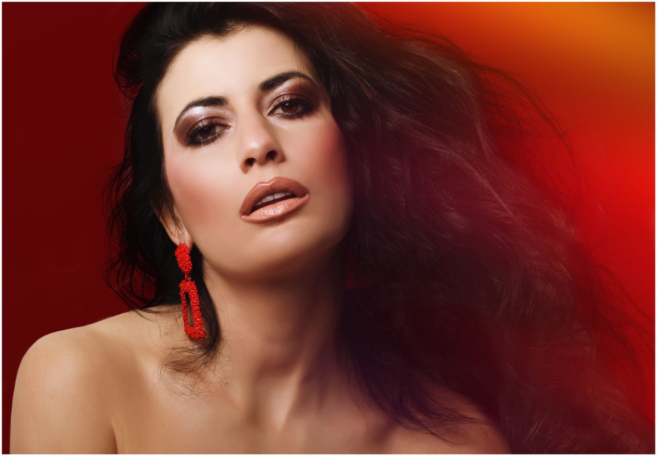 studio portrait of a glamorous woman with striking makeup and red earr