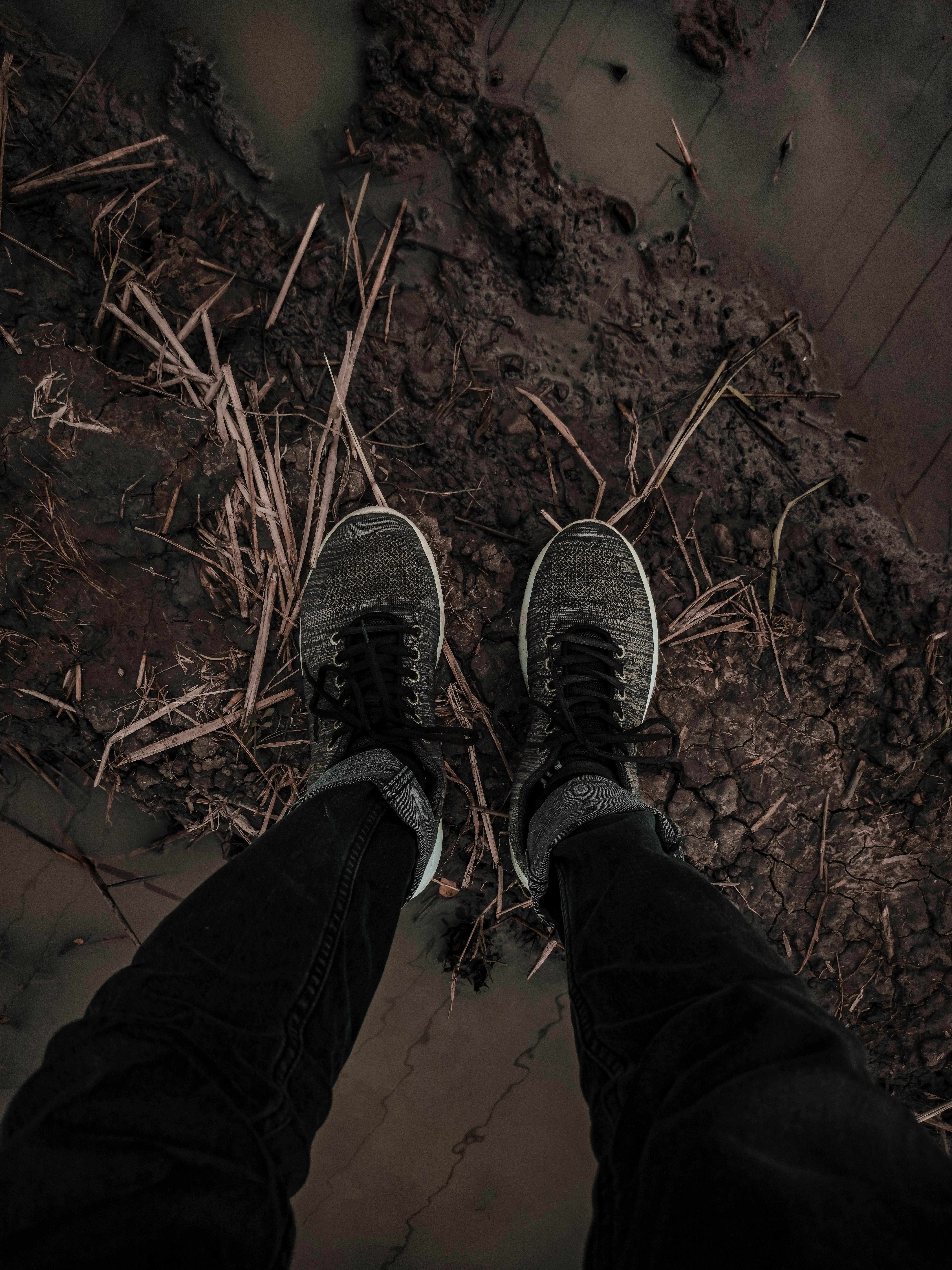 High-angle view of sneakers standing on muddy ground outdoors, ideal for adventure and travel themes.