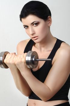 Woman in athletic gear lifting a dumbbell, showcasing strength and fitness.