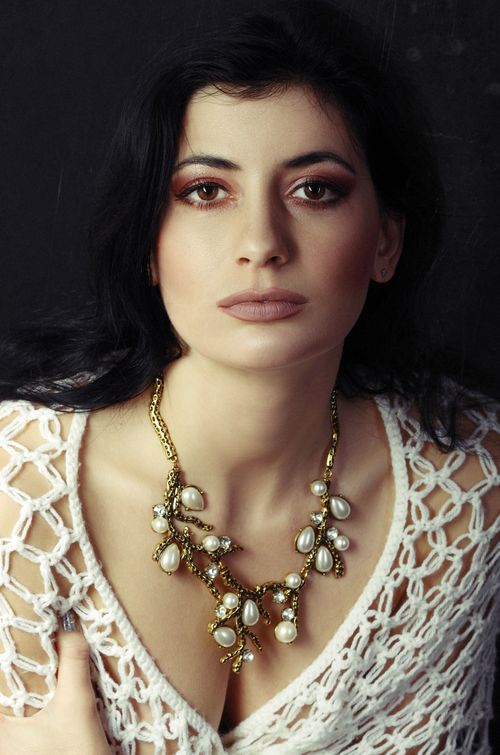 Free Striking portrait of a woman wearing a pearl and gold necklace, exuding elegance. Stock Photo