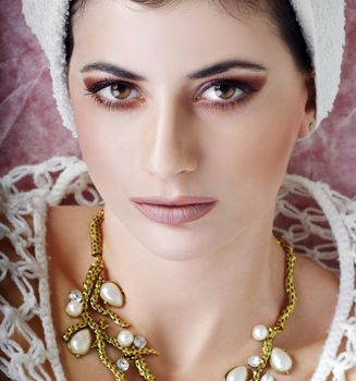 Close-up portrait of a woman with elegant makeup and a luxurious pearl necklace.