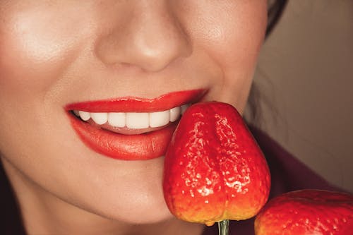 Woman With Red Lipstick Holding a Strawberry