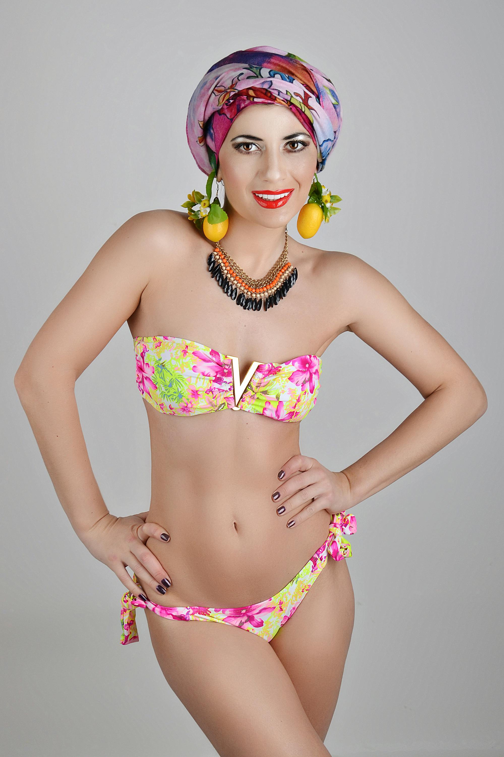 Colorful swimwear and accessories styled portrait of an adult woman in a studio setting.