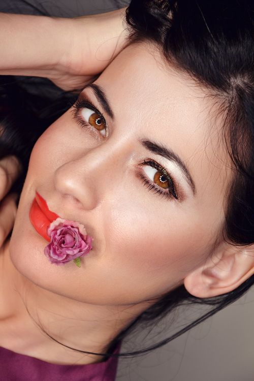 Free Close-up studio portrait of a woman with makeup and flower posing elegantly. Stock Photo