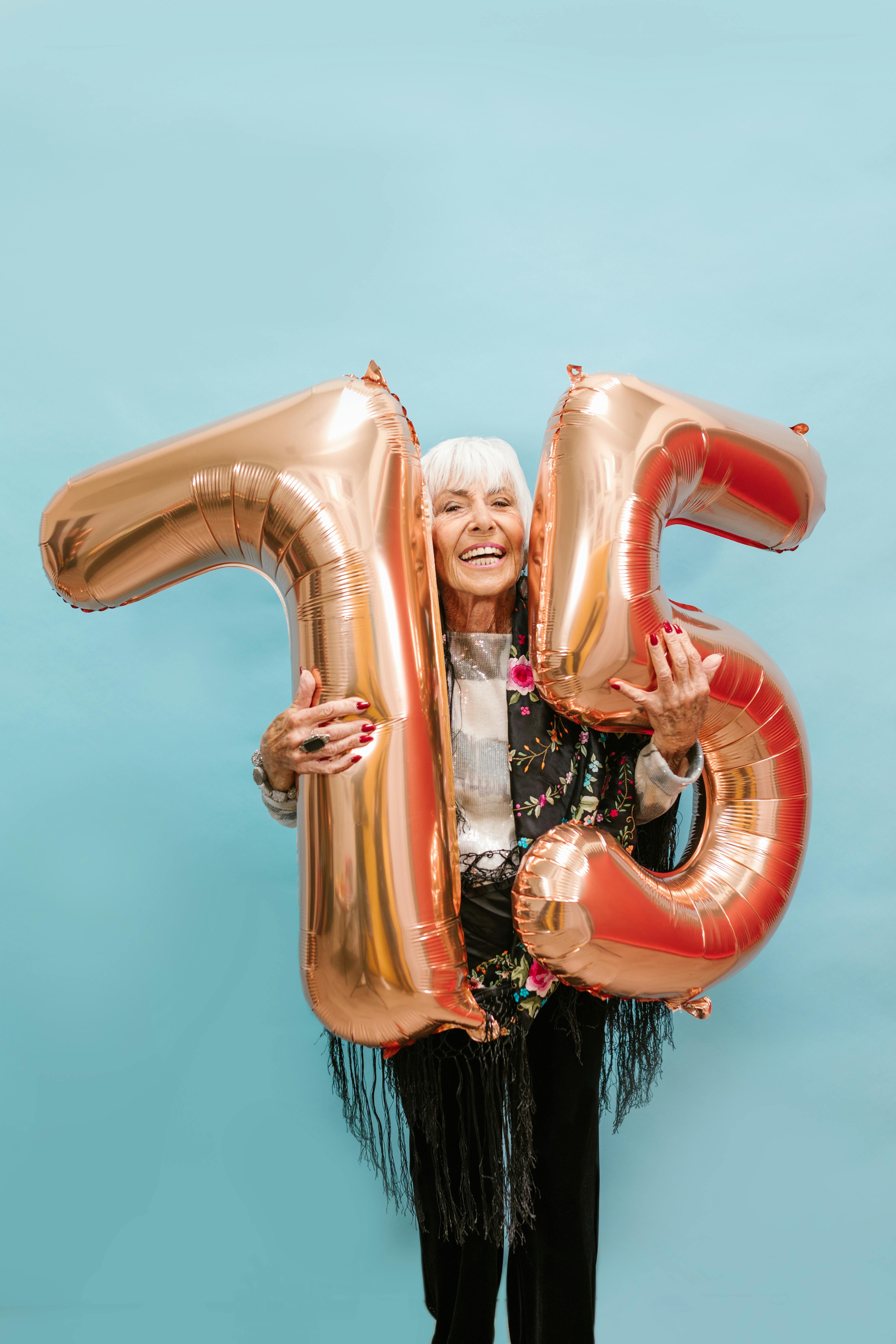 a happy old woman holding inflatable numbers