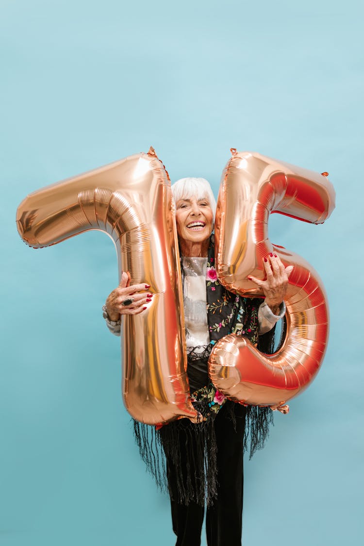 A Happy Old Woman Holding Inflatable Numbers