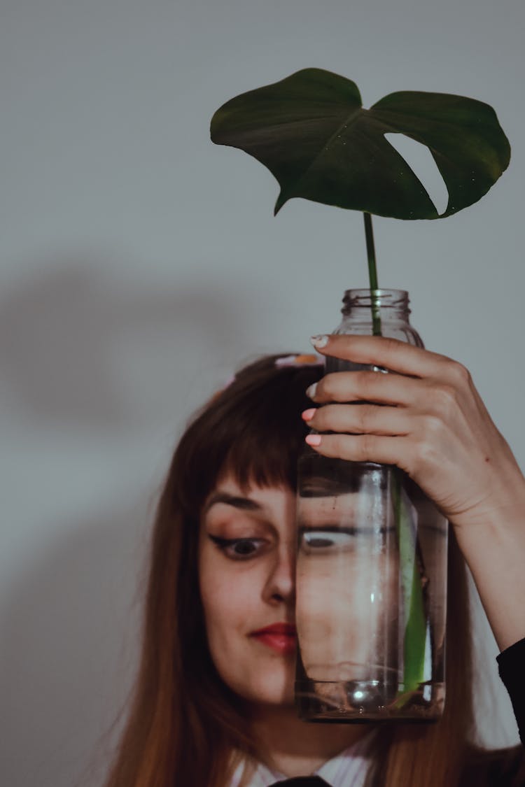 A Funny Woman Holding Clear Glass Bottle On Her Face